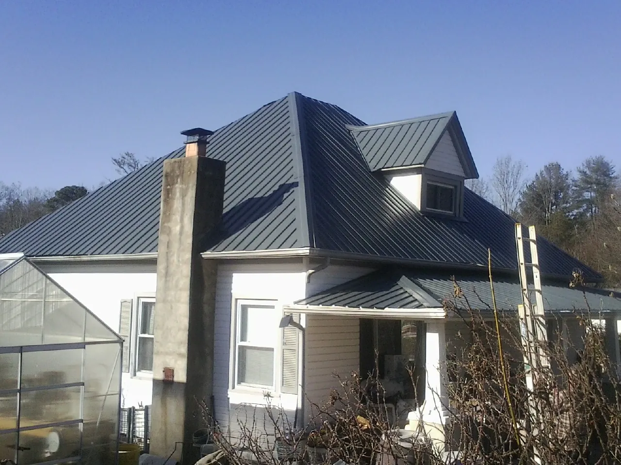 Dark blue standing seam metal roof on a white farmhouse with dormer — Slate & Tile Roof Repair by Roofing Brothers in Kaneville