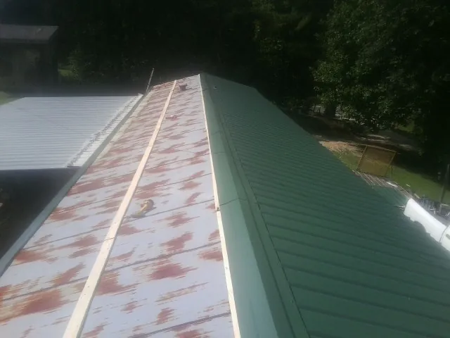 Old rusted panels beside newly installed green metal roofing — Wind Damage Roof Repair by Roofing Brothers in Kaneville