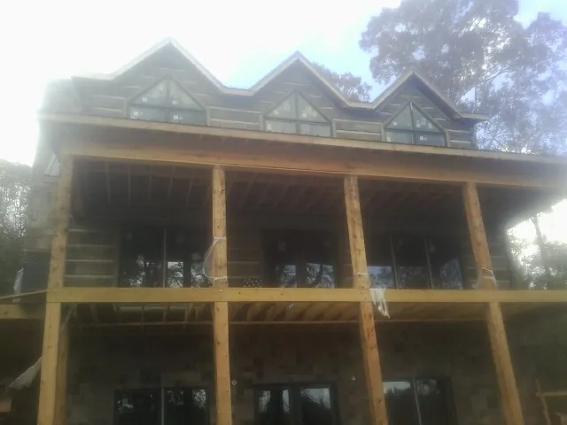 Dormers and porch framing on a large log home under construction — Roof Coating work by our crew in Kaneville
