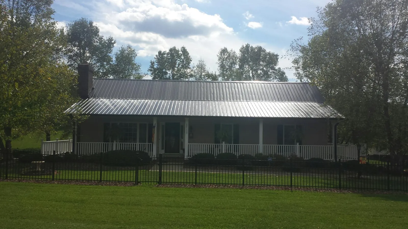 Gray metal roof on a brick ranch with a full width front porch — Gutter Guard Installation work by our crew in Kaneville