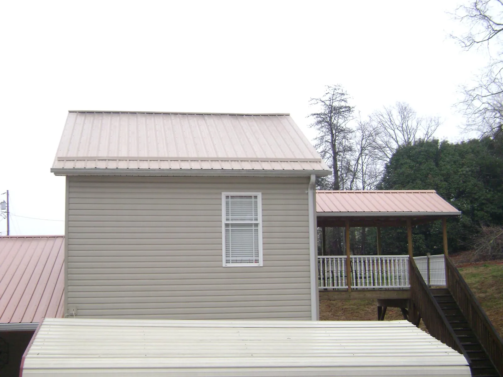 Tan metal roofs on a two story addition and attached porch, from a Roof Replacement job in Kaneville