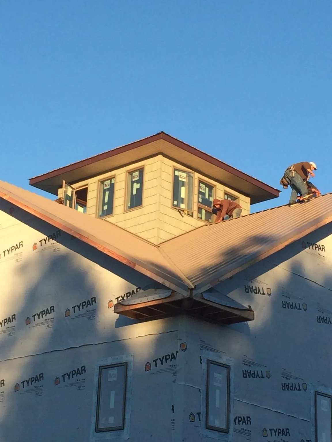 Roofers working around a rooftop cupola on a new metal roof at sunset — Roof Waterproofing in Kaneville by Roofing Brothers